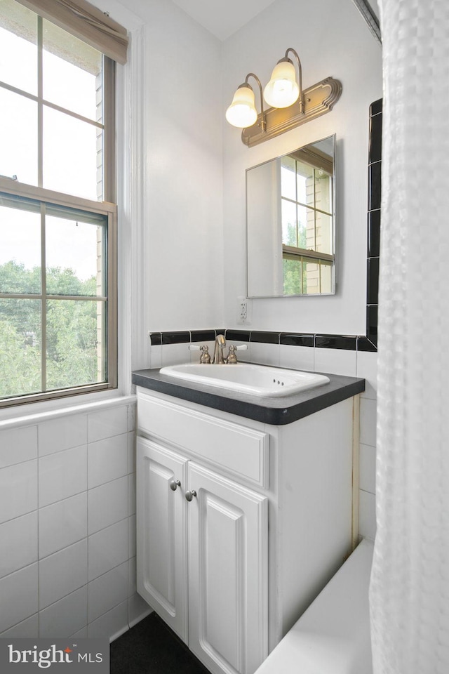 bathroom featuring plenty of natural light, tile walls, and vanity