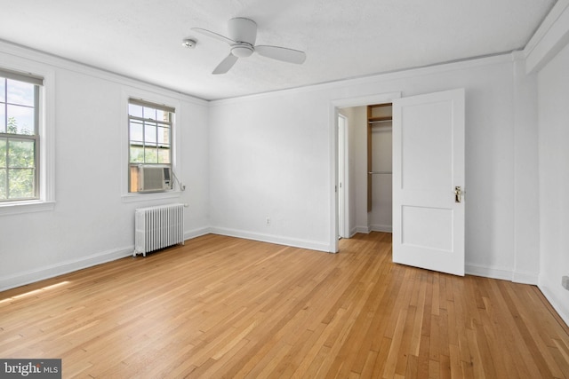 unfurnished bedroom featuring radiator, ceiling fan, light hardwood / wood-style flooring, cooling unit, and a closet