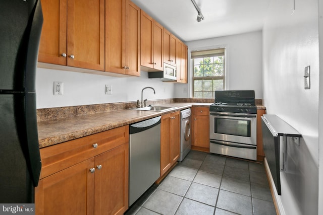 kitchen featuring sink, track lighting, washer / dryer, light tile patterned floors, and appliances with stainless steel finishes