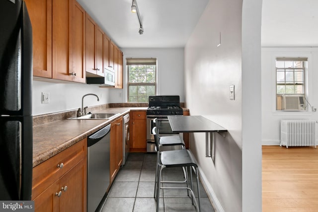 kitchen featuring radiator, sink, appliances with stainless steel finishes, light hardwood / wood-style floors, and washer / dryer