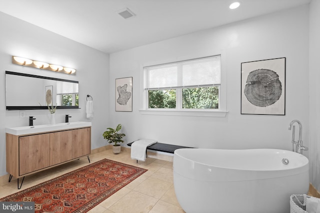 bathroom with tile patterned flooring, a washtub, vanity, and a wealth of natural light