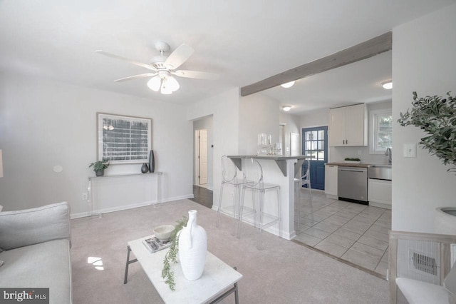 tiled living room featuring beamed ceiling, ceiling fan, and sink