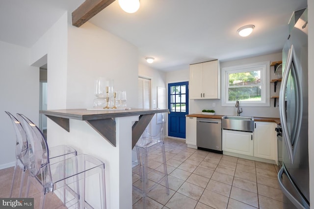 kitchen with sink, kitchen peninsula, a breakfast bar area, white cabinets, and appliances with stainless steel finishes