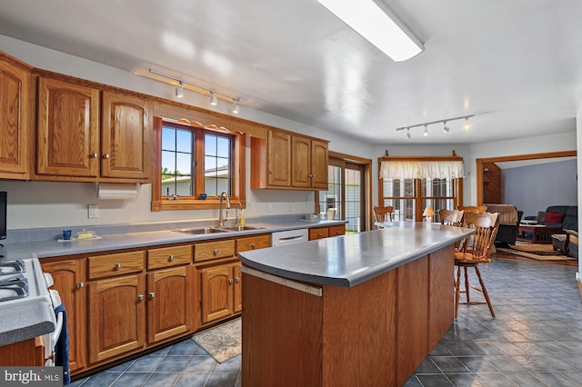 kitchen featuring a kitchen breakfast bar, rail lighting, white appliances, sink, and a center island