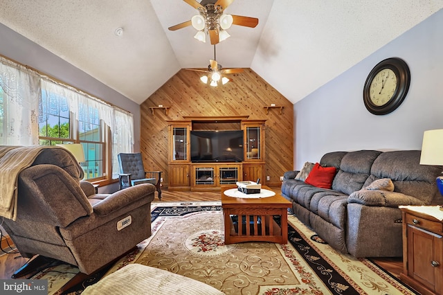 living room with hardwood / wood-style flooring, vaulted ceiling, ceiling fan, and wooden walls