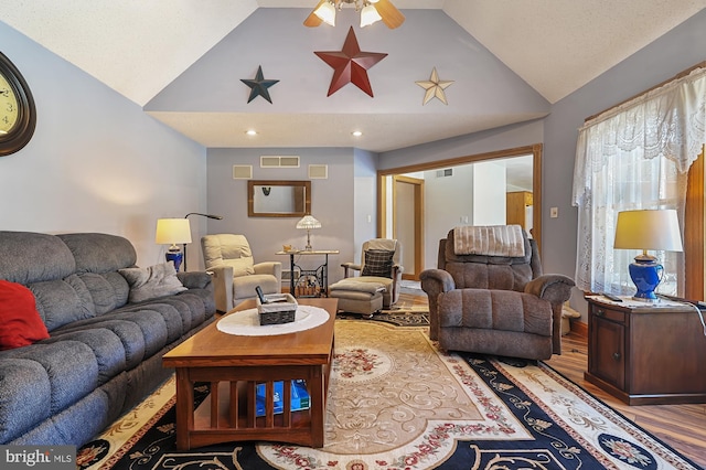 living room with hardwood / wood-style flooring, ceiling fan, and lofted ceiling