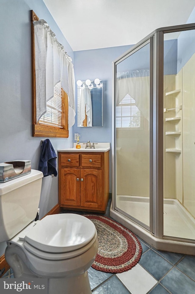 bathroom with tile patterned flooring, vanity, toilet, and an enclosed shower