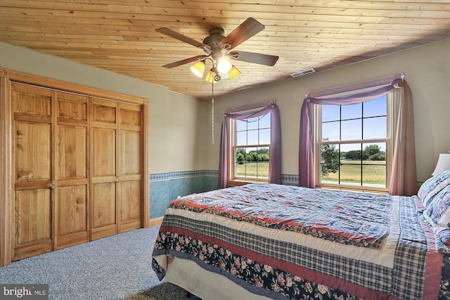 bedroom featuring ceiling fan, carpet floors, multiple windows, and wood ceiling