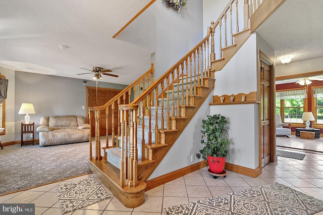 stairs featuring tile patterned flooring, ceiling fan, and a textured ceiling