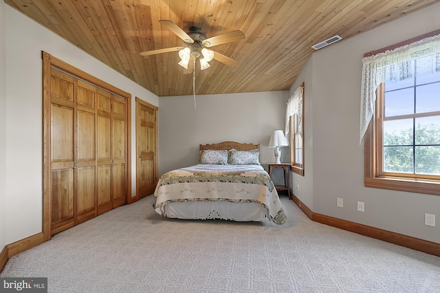 bedroom featuring carpet flooring, two closets, ceiling fan, and wood ceiling