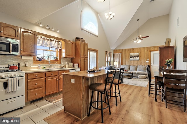 kitchen featuring gas range gas stove, light hardwood / wood-style flooring, high vaulted ceiling, backsplash, and a kitchen island