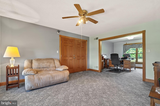 carpeted living room featuring ceiling fan and a textured ceiling