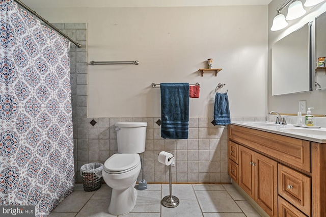 bathroom with walk in shower, tile patterned floors, toilet, vanity, and tile walls