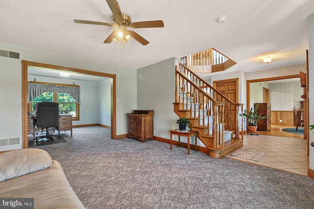 living room with carpet, ceiling fan, and a textured ceiling