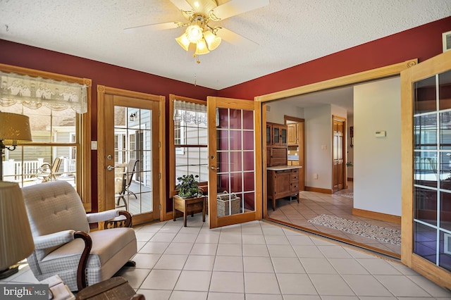 living area featuring ceiling fan, french doors, light tile patterned floors, and a textured ceiling