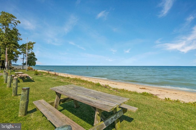 view of property's community with a view of the beach, a yard, and a water view