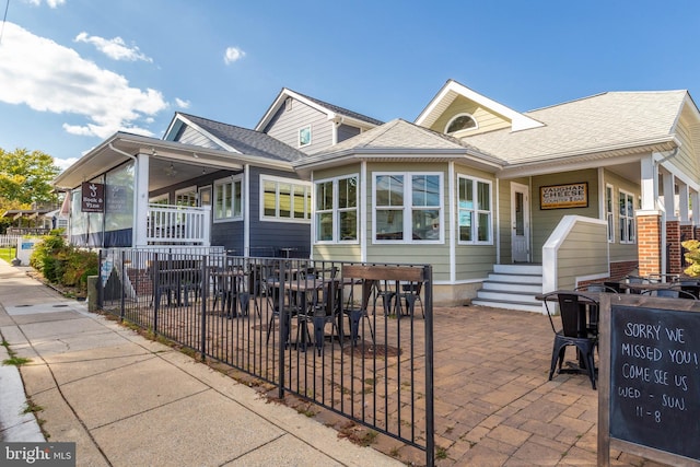 exterior space with a patio, roof with shingles, outdoor dining space, and fence