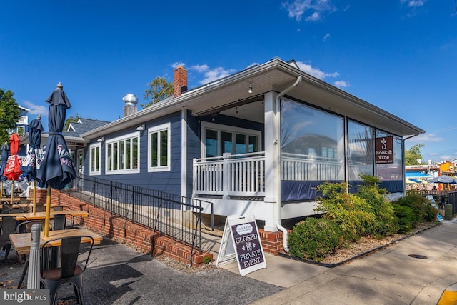 view of property exterior with a chimney, a sunroom, and fence