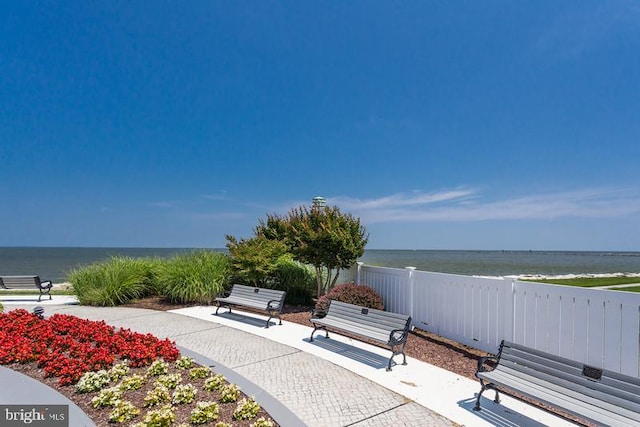 view of property's community with a patio, fence, and a water view