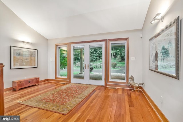 entryway with visible vents, baseboards, wood finished floors, and vaulted ceiling