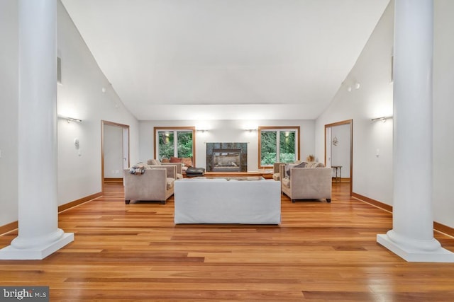 living room with light wood finished floors, plenty of natural light, and ornate columns