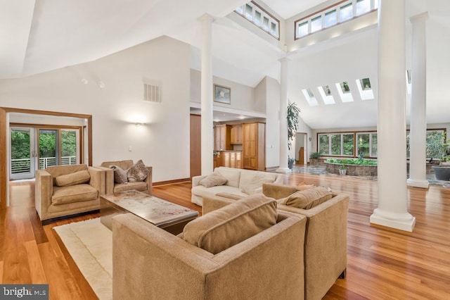 living area with plenty of natural light, wood finished floors, visible vents, and ornate columns