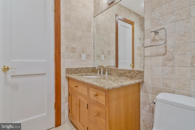 bathroom featuring toilet, tile walls, and vanity