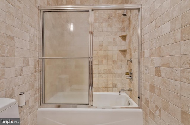 bathroom with toilet and combined bath / shower with glass door