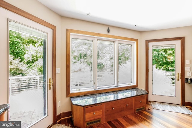 doorway to outside with wood finished floors, visible vents, and baseboards