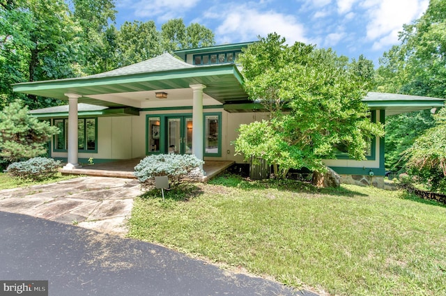 view of front of property with an attached carport, a front lawn, roof with shingles, covered porch, and driveway