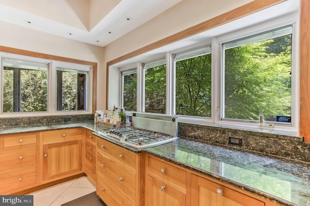 kitchen featuring light tile patterned floors, dark stone counters, plenty of natural light, and stainless steel gas cooktop