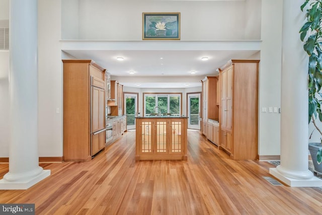 kitchen with light wood-type flooring, decorative columns, and dark countertops