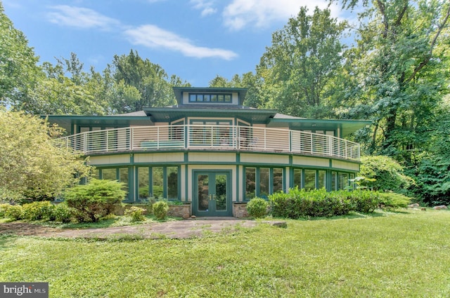 rear view of property with french doors, a yard, and a balcony