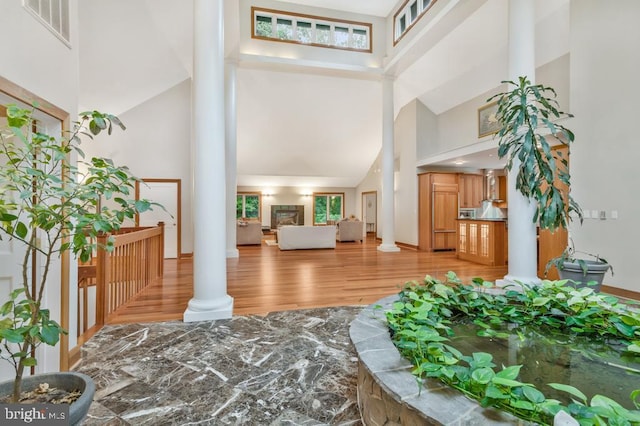 foyer featuring decorative columns, a high ceiling, visible vents, and light wood finished floors