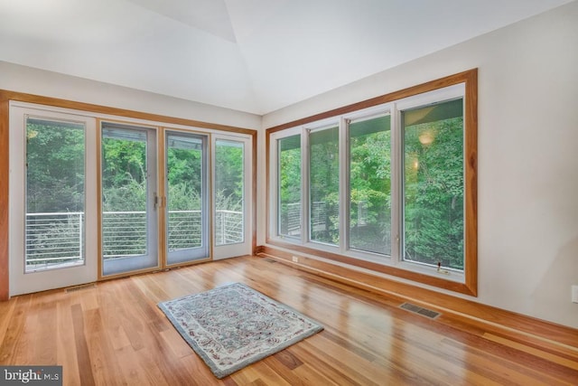 empty room featuring vaulted ceiling, visible vents, and wood finished floors