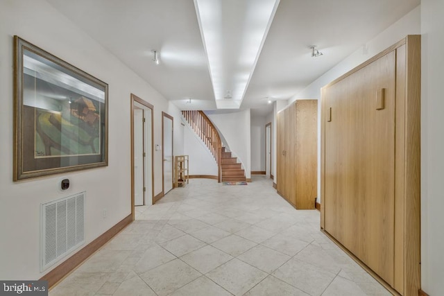 corridor with visible vents, stairs, and baseboards