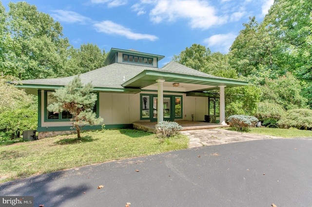 view of front of home with a front lawn, driveway, and a shingled roof