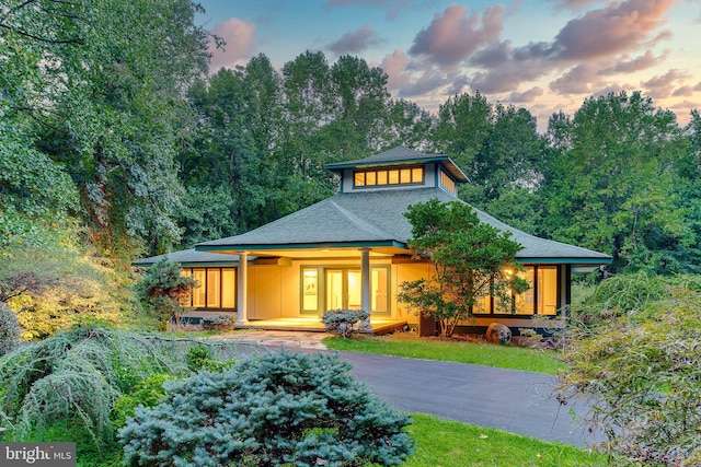 rear view of house featuring aphalt driveway and roof with shingles