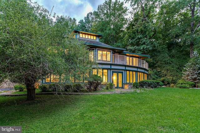 back of property with a yard, a balcony, and french doors