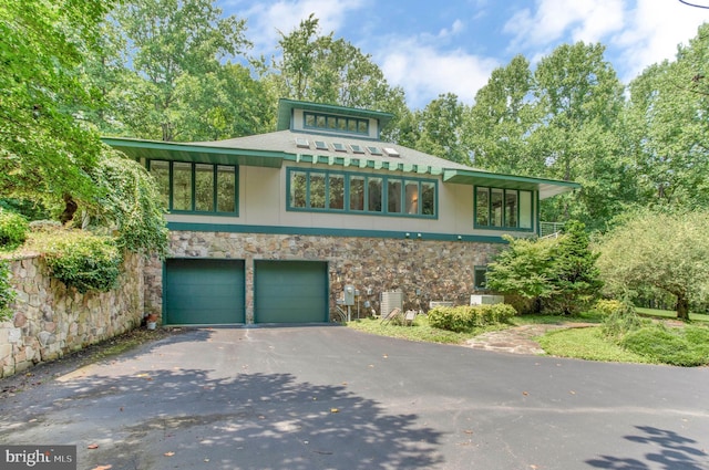 prairie-style home featuring aphalt driveway, a garage, and stone siding