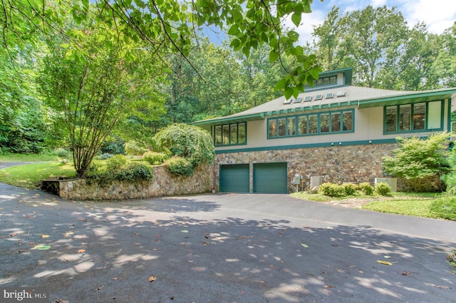 view of front of house featuring aphalt driveway, stone siding, and an attached garage