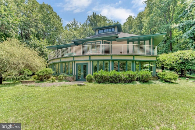 rear view of property with french doors, a yard, and a balcony