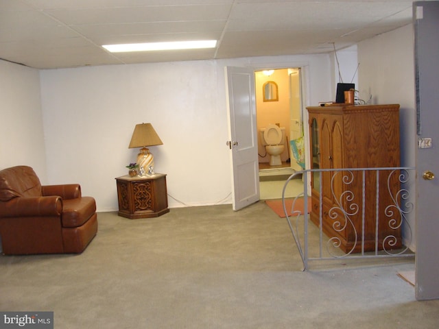 sitting room featuring a drop ceiling and carpet floors