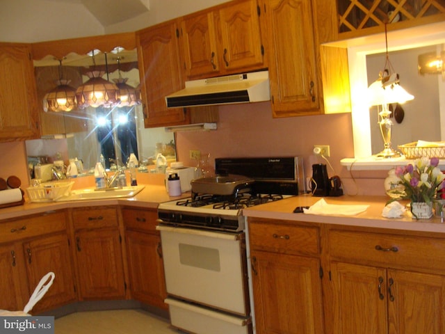 kitchen featuring white gas stove, under cabinet range hood, a sink, brown cabinetry, and light countertops