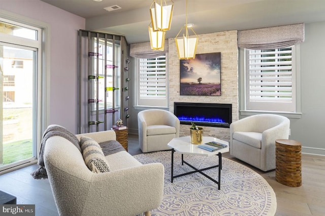 living room with wood-type flooring and a stone fireplace