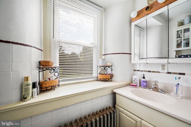 bathroom with vanity, plenty of natural light, and tile walls