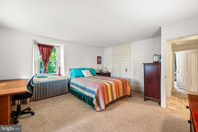 bedroom with light carpet and radiator heating unit