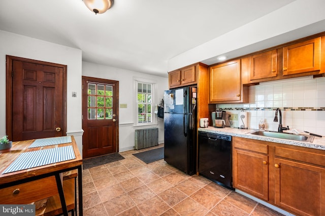 kitchen with tasteful backsplash, sink, black appliances, light tile patterned floors, and radiator heating unit