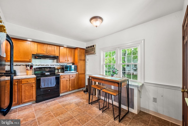 kitchen featuring a wall unit AC, backsplash, and black electric range