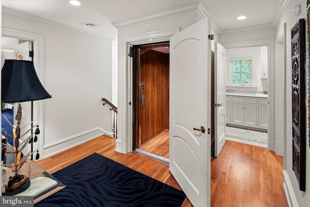 bedroom with ensuite bath, ornamental molding, and light hardwood / wood-style flooring